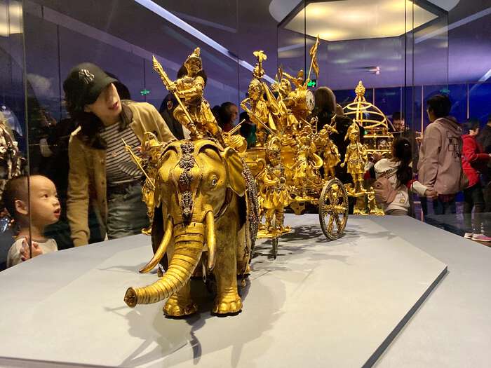 An ornate golden clock shaped like an elephant procession