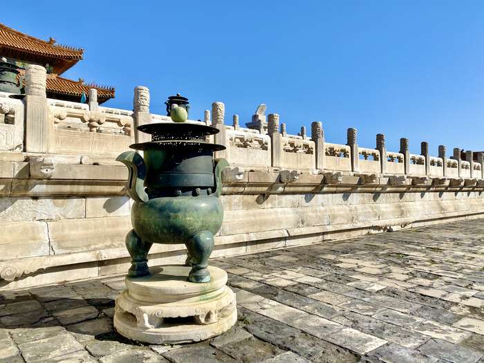 Bronze incense burner in front of a white stone wall