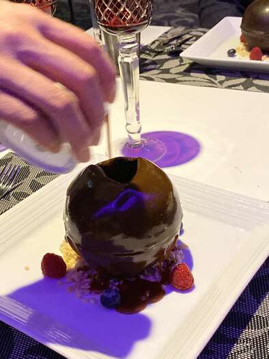 Chocolate sphere dessert being melted with warm sauce, 2 of 3
