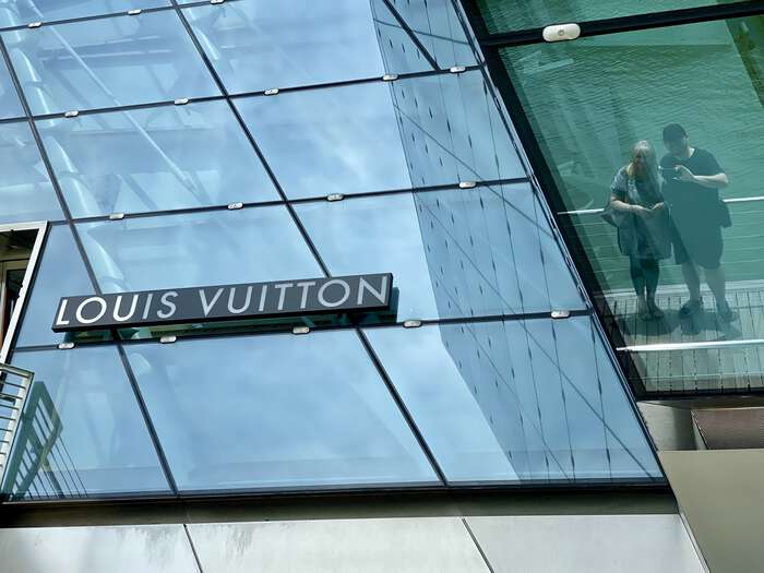 Zarino and Julijana reflected in the glass exterior of the Singapore Louis Vuitton store